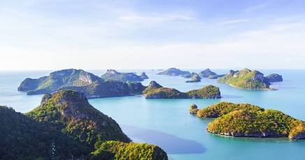 Sunlit green islands surrounded by calm blue water, seen through an open window
